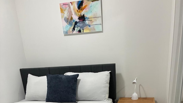 Un lit bien fait, avec une literie blanche et une tête de lit foncée.