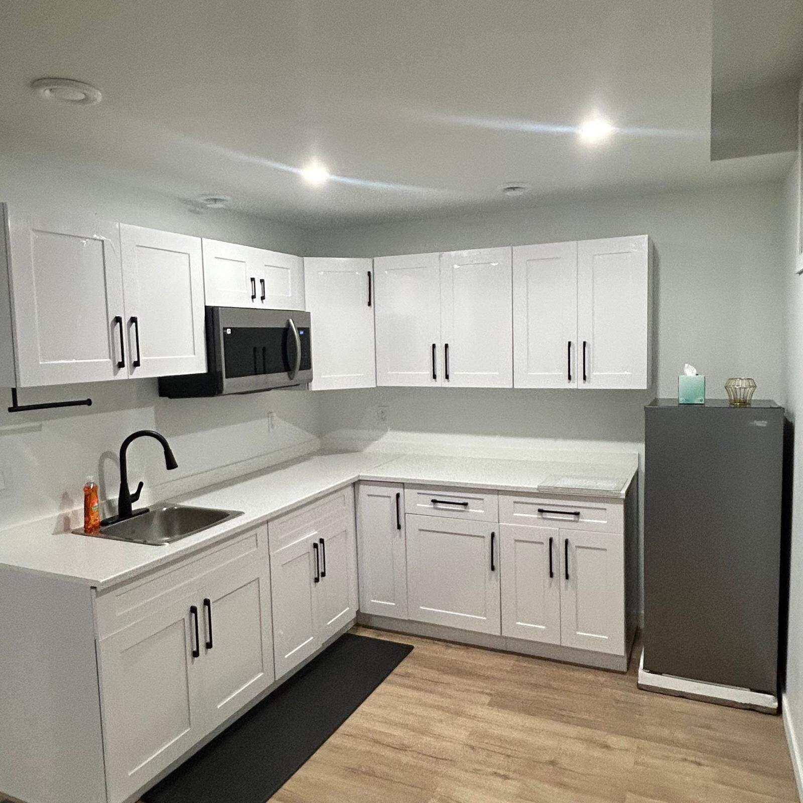 A modern kitchen with white cabinetry, a stainless steel sink, and a built-in microwave.