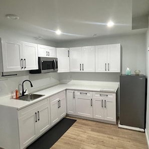A modern kitchen with white cabinetry, a stainless steel sink, and a built-in microwave.