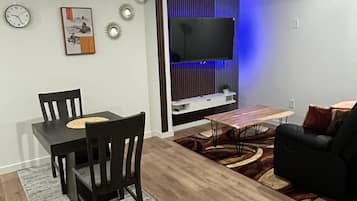 Een moderne woonkamer met een eetgedeelte, een wandmontage flatscreen televisie en een bank.