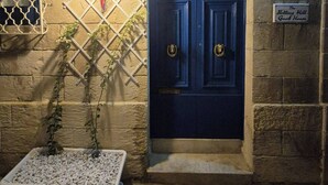 A blue door with a metal gate, a potted plant, and a sign indicating 'The Notting Hill Guest House.'