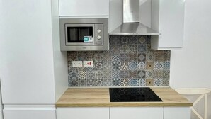 A modern kitchen with a microwave, stove, and patterned backsplash.