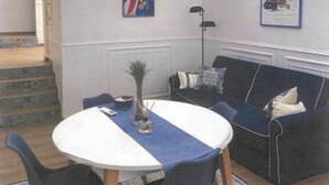A room with a round dining table, two chairs, a blue sofa, and a blue and white rug.