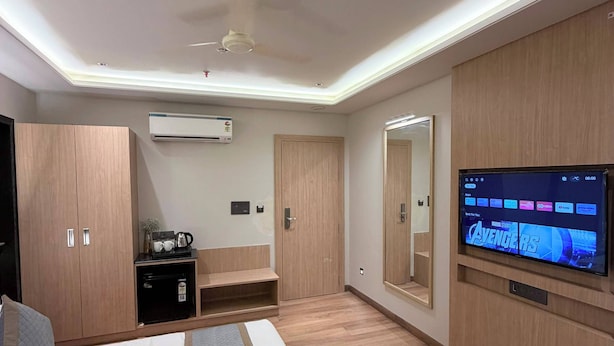 A modern hotel room with a bed, a TV, a wardrobe, a desk, and an air conditioning unit. - Hotel Ramaya Luxury  (Jaipur)
