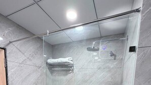 A modern bathroom with a glass-enclosed shower, marble walls, and a visible towel rack. - Hotel Ramaya Luxury  (Jaipur)