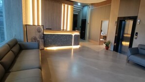 A modern hotel lobby with a reception desk, sofas, and a potted plant. - Hotel Ramaya Luxury  (Jaipur)