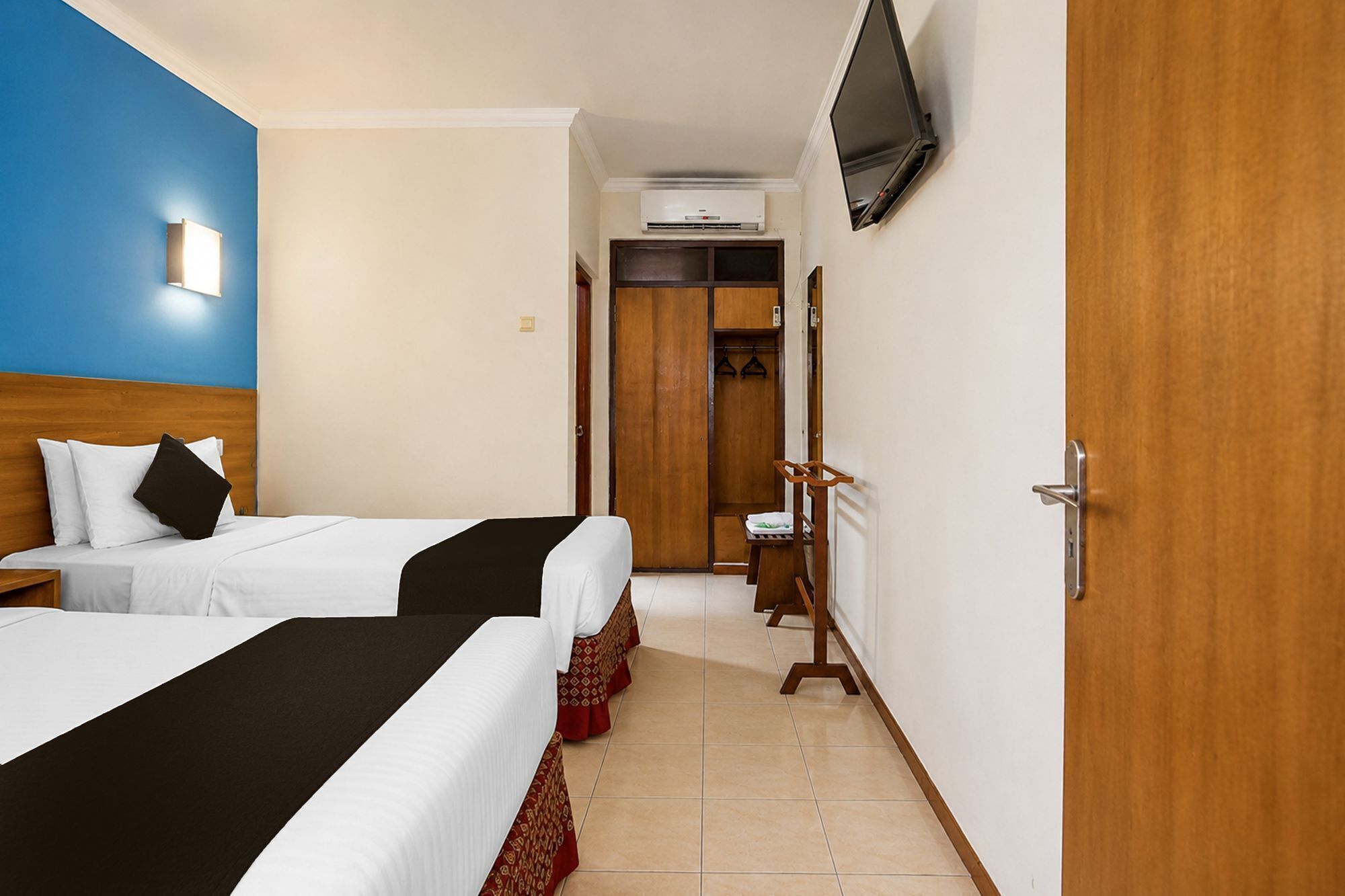 Une chambre d’hôtel avec deux lits, une armoire, un téléviseur et un appareil de climatisation.