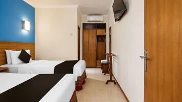 Une chambre d’hôtel avec deux lits, une armoire, un téléviseur et un appareil de climatisation.