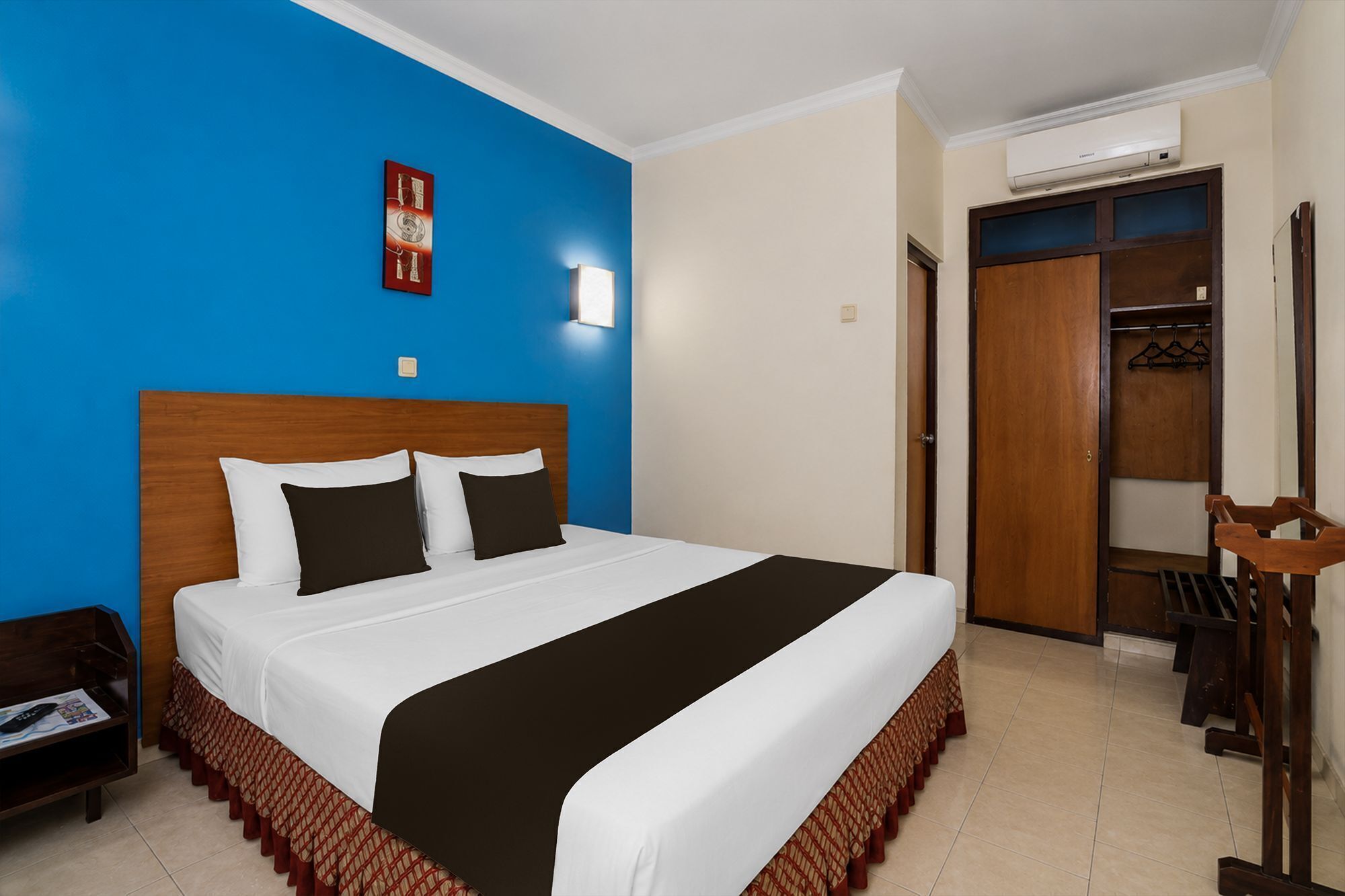 A hotel room with a large bed, a wardrobe, a mirror, and a small table.