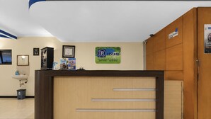 A reception desk with a wooden finish, a framed certificate on the wall, and a sign for 'Lestari' hotel. - Townhouse Oak Hotel Lestari (Kaliwates)