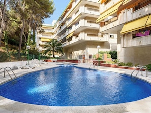 A swimming pool with a circular shape, surrounded by a concrete deck, with a multi-story building in the background. - Apartment Uolas by Interhome (Salou)