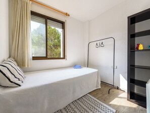 A single-bed room with a window, a bedside table, a wardrobe, and a patterned rug. - Apartment Uolas by Interhome (Salou)