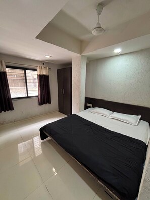 A bedroom with a bed, a window with curtains, a wardrobe, and a ceiling fan.