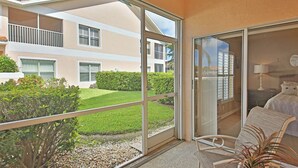 A room with a sliding glass door leading to a balcony, a bed with a headboard, and a small table with a chair. - First Floor With a View of the Lake (Naples)