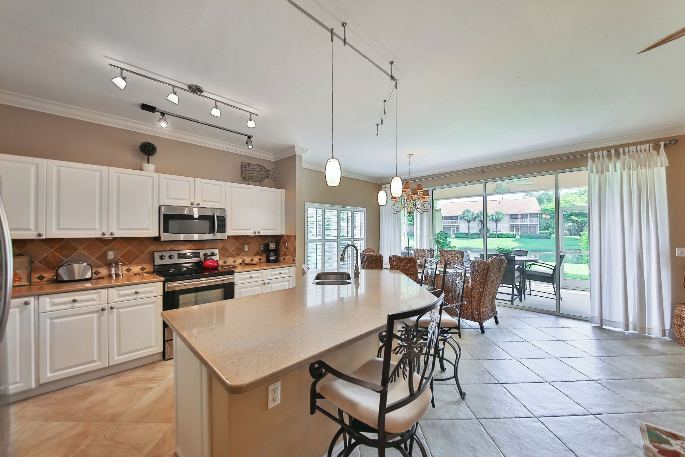 A spacious kitchen with a central island, modern appliances, and a dining area with wicker chairs.