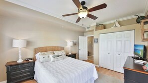A bedroom with a bed, nightstands, a desk, a ceiling fan, and a door leading to another room. - First Floor With a View of the Lake (Naples)