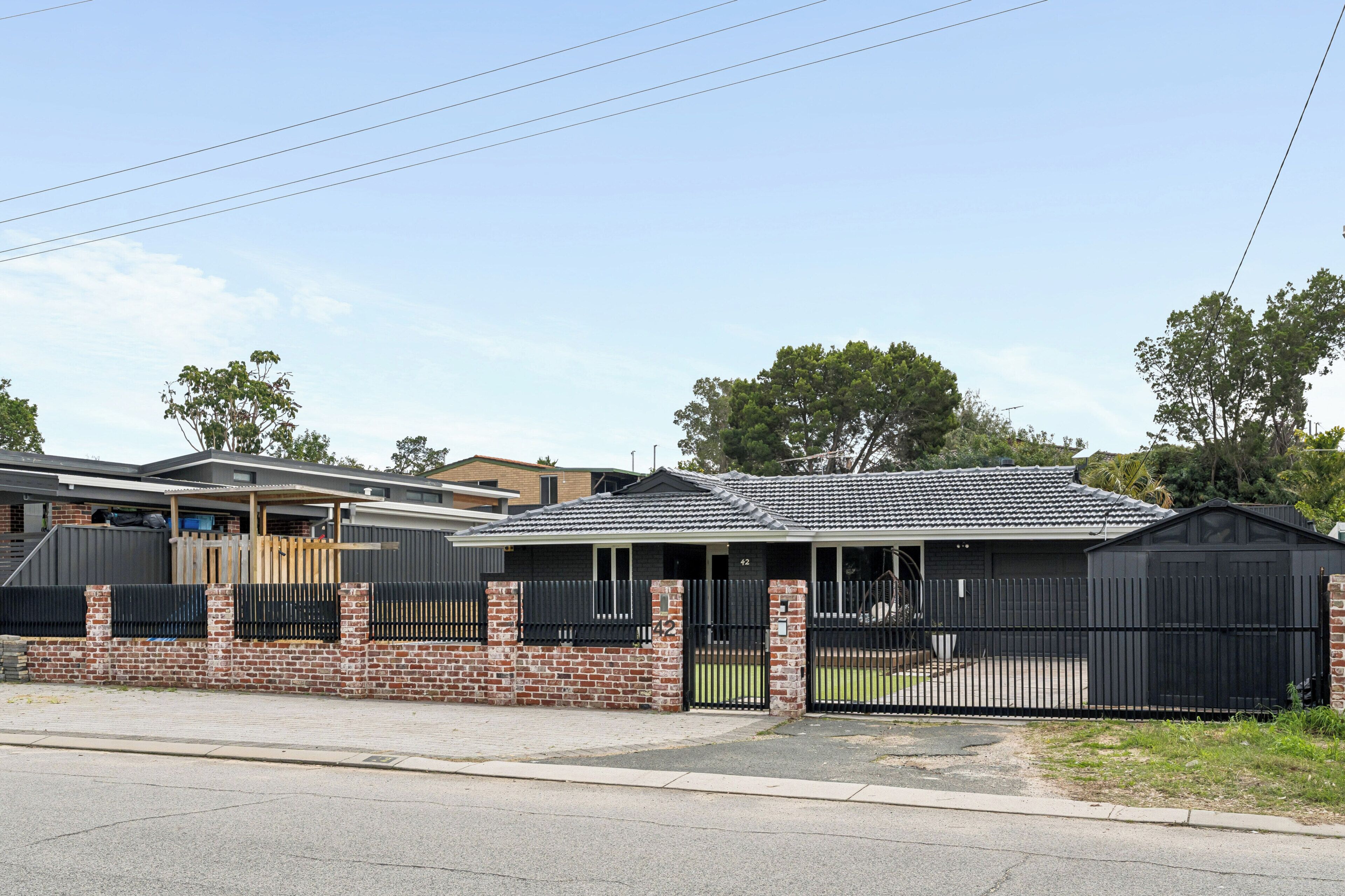 A residential property with a brick wall, a metal gate, and a tiled roof.