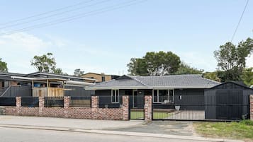 A residential property with a brick wall, a metal gate, and a tiled roof.