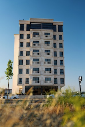 Un hotel de varios pisos con fachada simétrica, amplias ventanas y una entrada central.