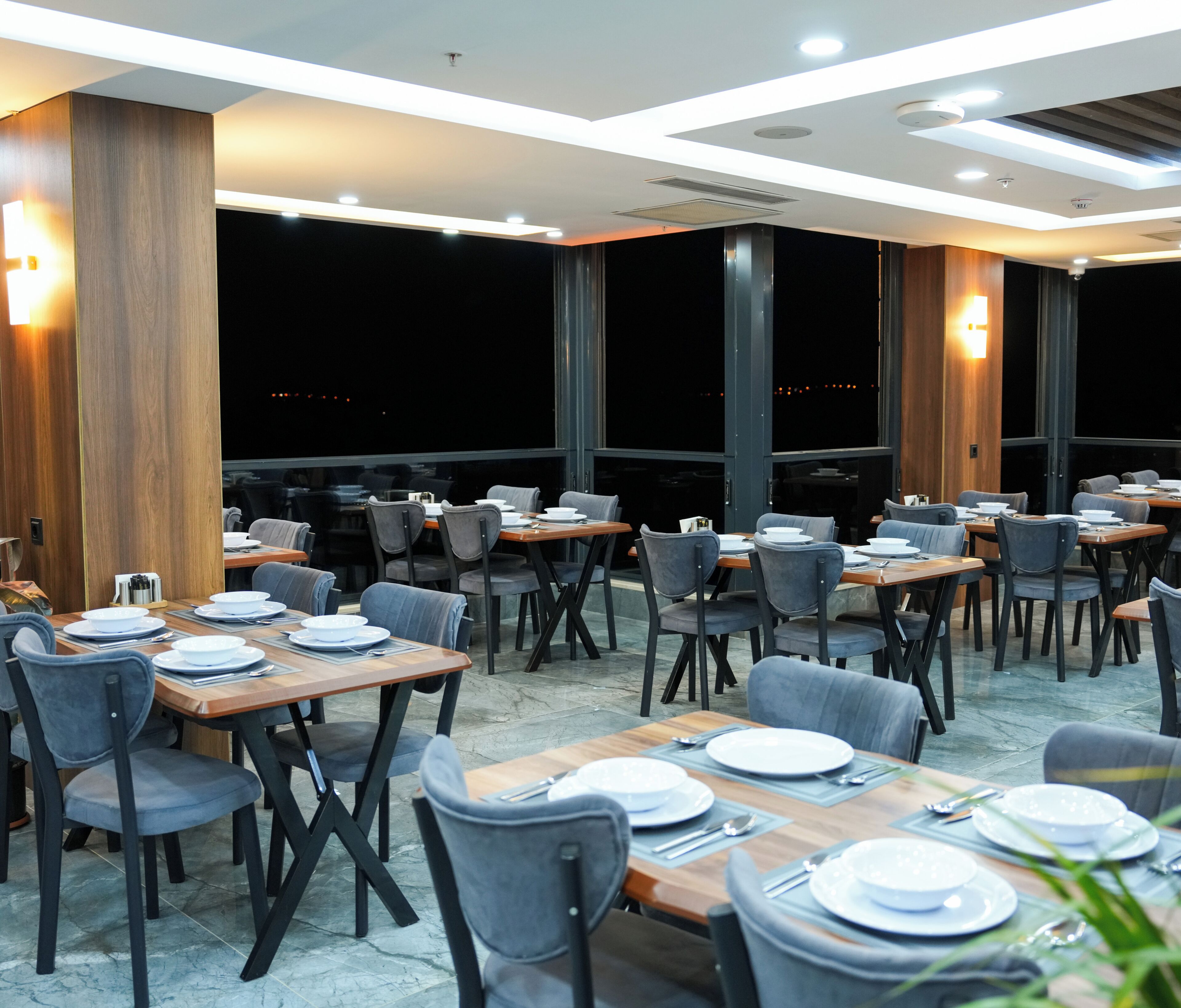 Ein Restaurant mit gedeckten Tischen, Stühlen und Blick auf den Nachthimmel.