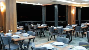 Ein Restaurant mit gedeckten Tischen, Stühlen und Blick auf den Nachthimmel.