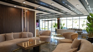 Un vestíbulo moderno con un amplio sofá modular, sillones, una mesa de centro y una planta en maceta.