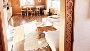 A wooden interior with a dining area, sofa, and a view through a window. - An authentic chalet atmosphere with mountain views (Flühli)