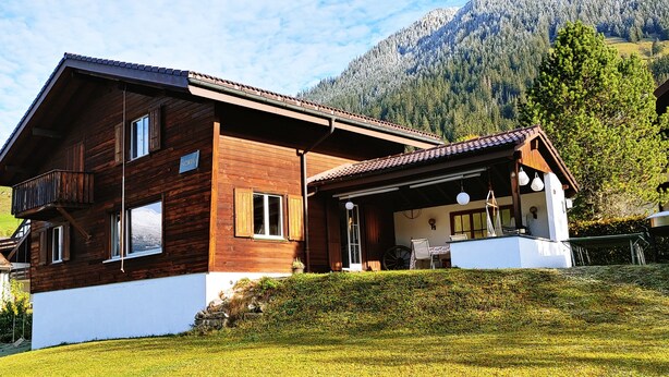 A wooden chalet with a balcony, a covered porch, and a view of a mountain. - An authentic chalet atmosphere with mountain views (Flühli)