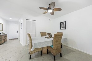 A dining area with a table, chairs, and a ceiling fan. - Walk to the Beach from Vanderbilt Villas (Naples)