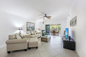 A living room with a sofa set, a coffee table, a TV, and a ceiling fan. - Walk to the Beach from Vanderbilt Villas (Naples)