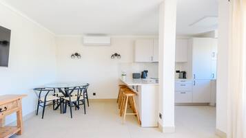 Una cocina moderna con armarios blancos, una isla central y taburetes de bar.