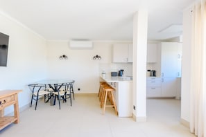 Una cocina moderna con armarios blancos, una isla central y taburetes de bar.