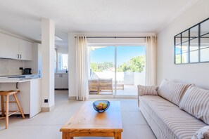 Un appartement moderne comprenant une cuisine, un coin repas avec une table, un canapé et une porte-fenêtre coulissante donnant sur un balcon.