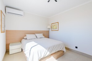 A bedroom with a bed, bedside tables, an air conditioning unit, a lamp, and a framed picture on the wall. - Jardins do Golfe Top Floor Retreat (Loulé)