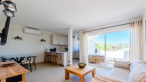 A modern living space with a dining area, kitchen, and a balcony with a view. - Jardins do Golfe Top Floor Retreat (Loulé)