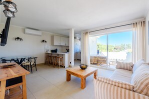 A modern living space with a dining area, kitchen, and a balcony with a view. - Jardins do Golfe Top Floor Retreat (Loulé)