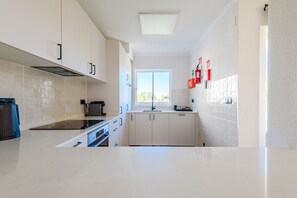 Una cocina moderna con armarios blancos, una estufa negra y un ventanal con vistas.