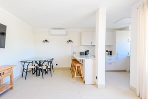 A modern kitchen with white cabinets, a central island, and bar stools. - Jardins do Golfe Top Floor Retreat (Vale do Lobo)