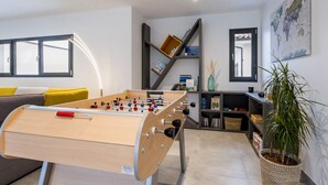 A modern living room with a foosball table, a sofa with yellow cushions, a bookshelf, and a large world map on the wall. - Spacious house in a quiet area (La Haie-Fouassière)
