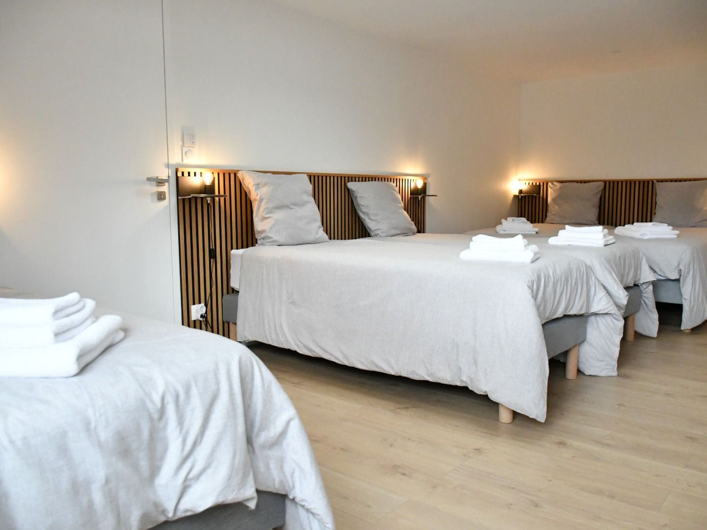 Une chambre d’hôtel avec deux lits, chacun doté d’une tête de lit, de tables de chevet et de lampes.