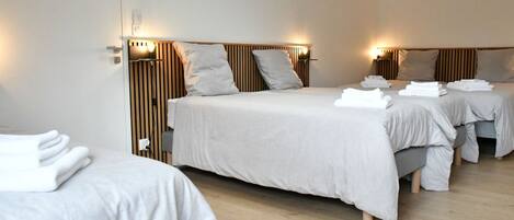 Ein Hotelzimmer mit zwei Betten, jeweils mit Kopfteil, Nachttischen und Lampen.
