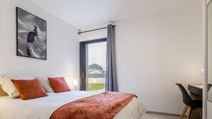 A modern bedroom with a large bed, a desk, and a window with curtains. - Spacious house in a quiet area (La Haie-Fouassière)