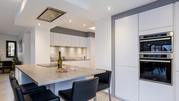 A modern kitchen with a central island, built-in ovens, and a dining area with bar stools. - Spacious house in a quiet area (La Haie-Fouassière)
