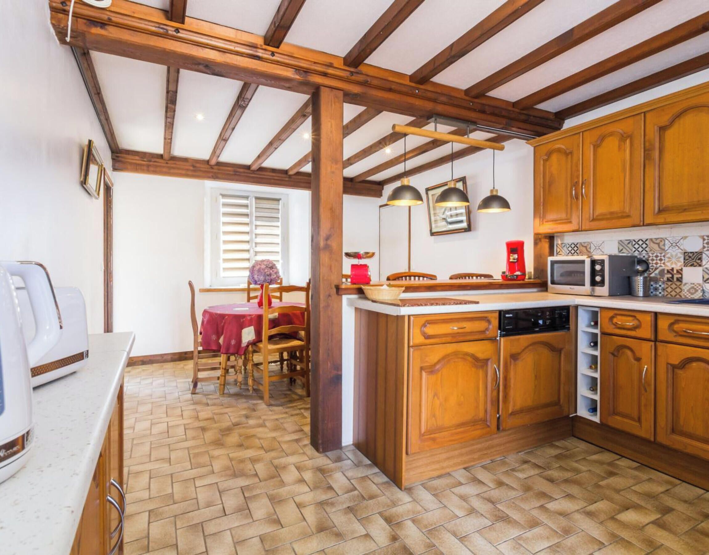 Una cucina con mobili in legno, un tavolo da pranzo con sedie, un forno a microonde e una macchina per il caffè.