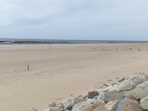 A wide sandy beach with a rocky shoreline in the foreground. - Ideal house, pets welcome - 6 guests (Portbail)