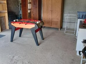Ein Zimmer mit einem Kicker, einem weißen Schrank und einem Holzschrank.