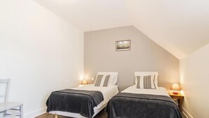 Ein Schlafzimmer mit zwei Betten, jeweils mit einem Kissen und einem Nachttisch mit Lampe.