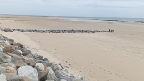 Ein Strand mit felsigem Ufer und blauem Himmel.