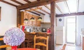 Eine Küche mit Holzausstattung, einem Esstisch mit Stühlen und einer Blumenvase.