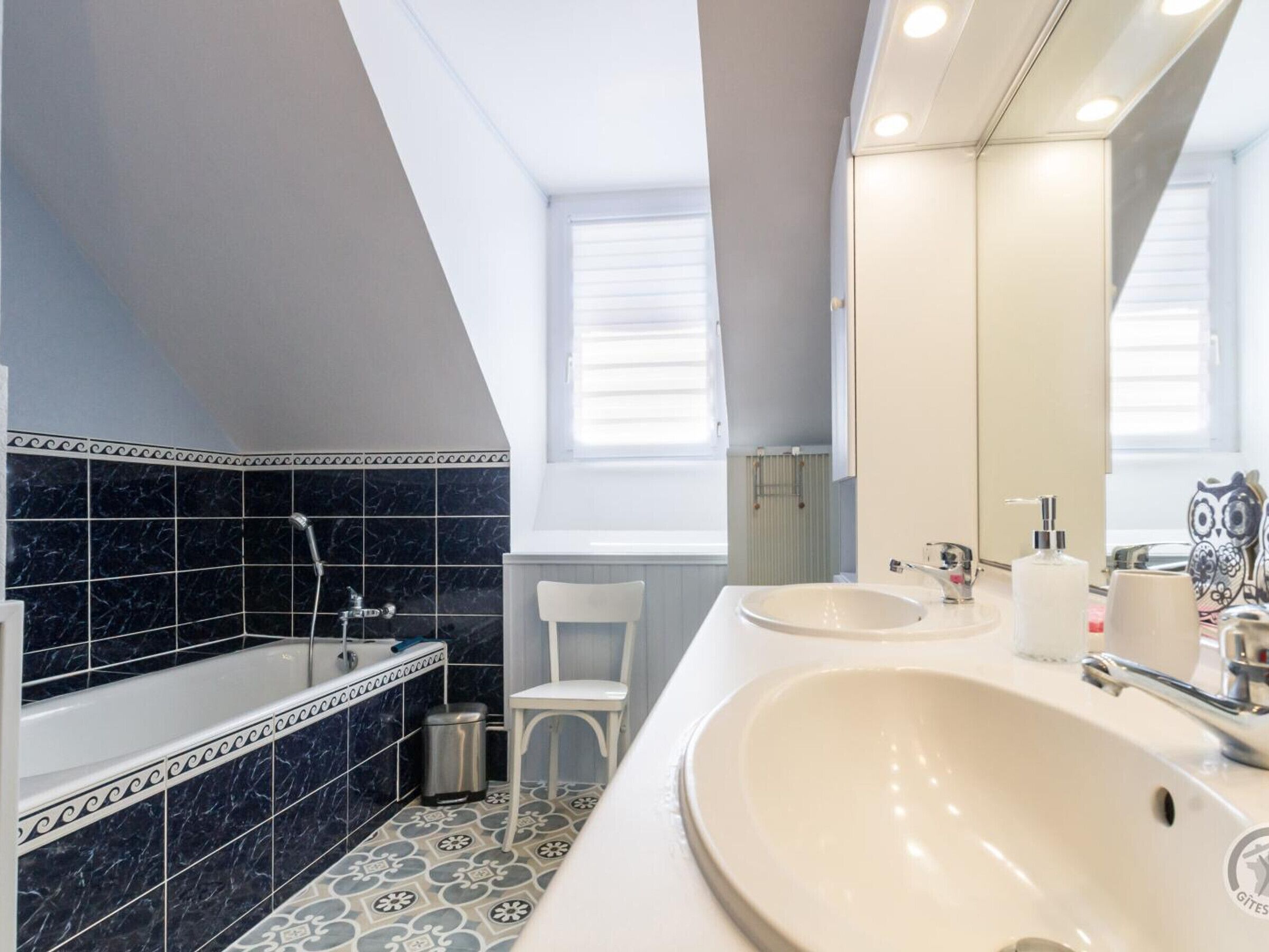 A modern bathroom with a bathtub, two sinks, and a large mirror.